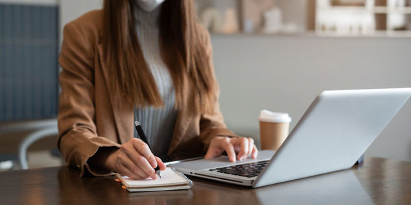 Midsection of woman using laptop at office