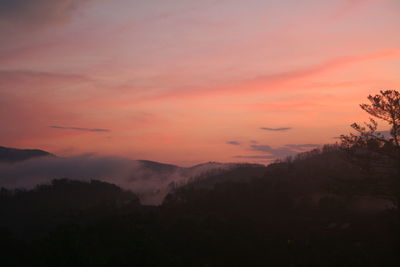 Scenic view of silhouette mountains against orange sky