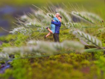 Side view of a figurine couple embracing amid stalks