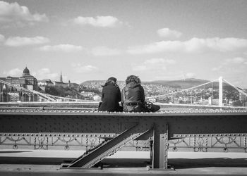 People on bridge against sky in city