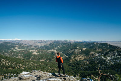 Man standing on mountain against blue sky