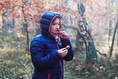 Woman smelling mushrooms standing in forest