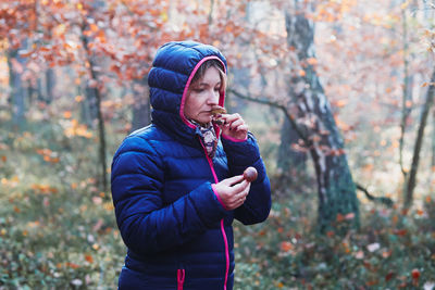 Man looking at camera while standing in forest during winter