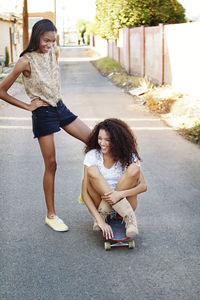 Happy friends with skateboard on road in town