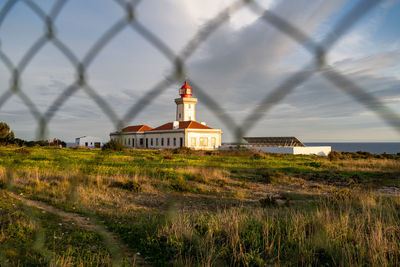 View of lighthouse on field against cloudy sky