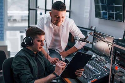 Conception of teamwork. two guys is indoors in the radio studio is busy by broadcast.