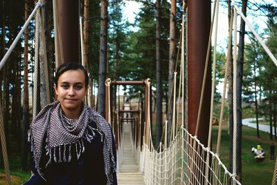 Portrait of young woman standing on rope bridge