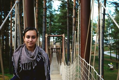 Portrait of young woman standing against trees