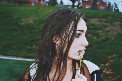 Close-up of young thoughtful woman holding flower seed