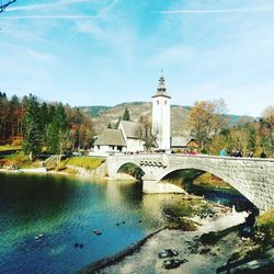 Bridge over river by mosque against sky