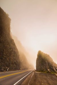 Empty road by mountain against sky