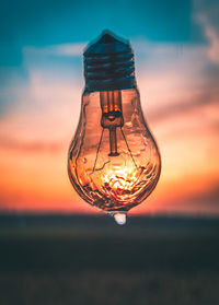 Close-up of illuminated light bulb on field