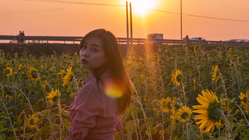 Portrait of woman standing on field against yellow sky