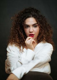 Portrait of young woman looking away against black background