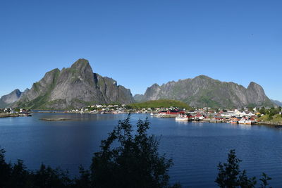 Scenic view of sea and mountains against clear blue sky