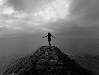 Rear view of man standing on shore against sky