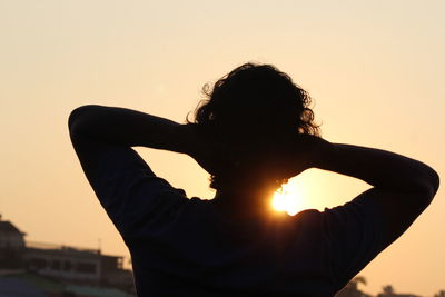 Rear view of silhouette woman standing against sky during sunset