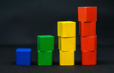 Stack of multi colored toy on wood against black background