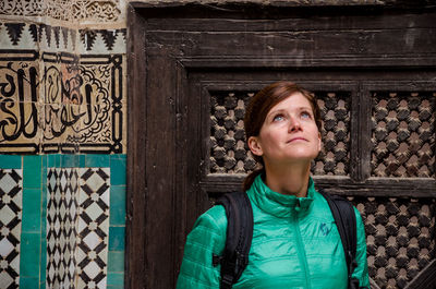 Portrait of young woman standing against entrance