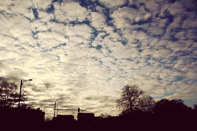 Low angle view of silhouette trees against cloudy sky