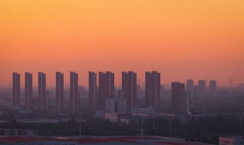 Modern buildings against sky during sunset