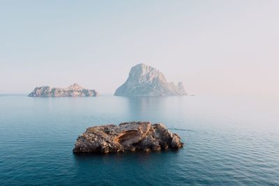 Rock formation in sea against clear sky