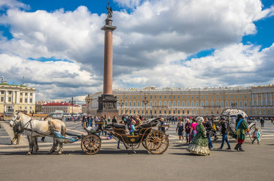 Horse cart in city against cloudy sky