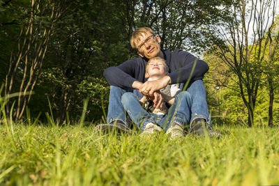 Portrait of young man using laptop while sitting on field