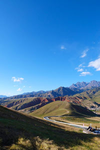 Scenic view of landscape and mountains against blue sky