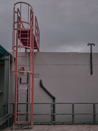 Metallic structure by factory against sky