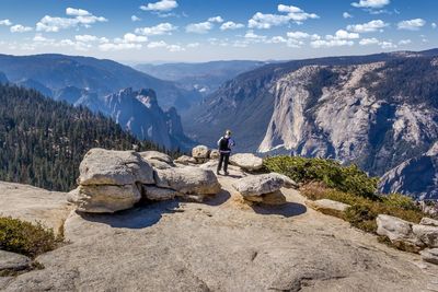 Woman standing on rock by mountains against sky