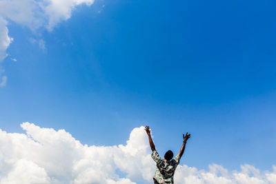 Low angle view of man climbing on blue sky