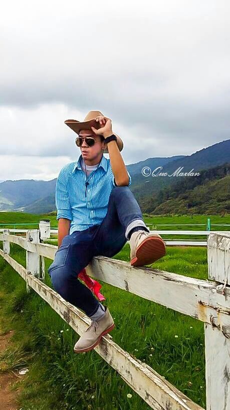 sky, full length, lifestyles, leisure activity, casual clothing, cloud - sky, mountain, grass, landscape, field, cloudy, person, mountain range, cloud, young adult, standing, grassy, nature