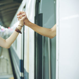 Cropped image of couple holding hands at railroad station platform