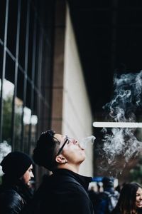 Side of young man emitting smoke