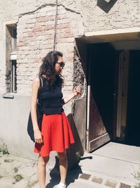 Young woman standing outside building on sunny day