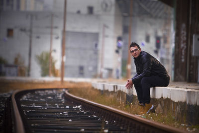 Portrait of man sitting at railroad station platform