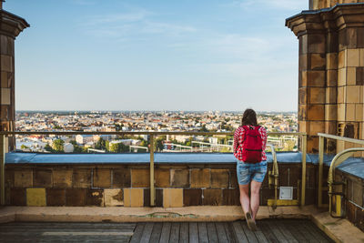 Rear view of woman standing on terrace against cityscape