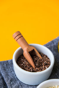 Wooden spoon with flax seeds lies in a white mortar on a yellow background. healthy eating. keto 