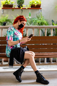Young woman using mobile phone while sitting on camera