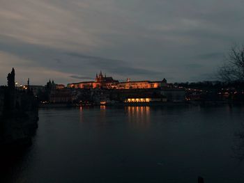 River by illuminated city against sky at dusk