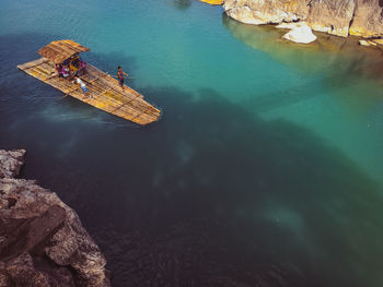 High angle view of people on wooden raft over sea