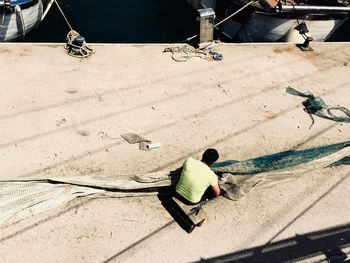 High angle view of working on fishnet at harbor