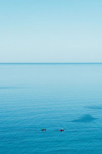 Scenic view of two kayakers on the sea against clear sky, calm and tranquil scene of adventure