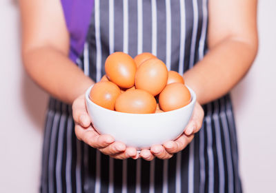 Close-up of hand holding eggs in bowl