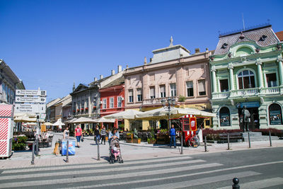 People on street against buildings in city