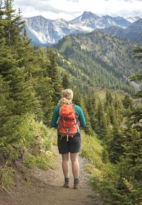 Rear view full length of backpack hiker standing against mountains