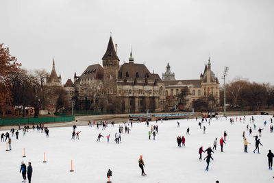 People skating on ice on an ice skating rick with a castle in the background