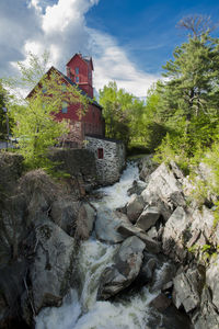 Rocks by river and buildings against sky