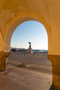 Angel statue of victory at sunset framed in an arch.